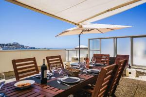 una mesa con copas de vino y una sombrilla en el balcón en CLEO KEYWEEK Apartment with terrace sea views swimming pool, en Biarritz