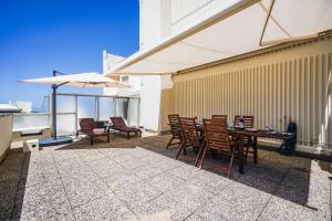 Un patio con una mesa y sillas y una sombrilla. en CLEO KEYWEEK Apartment with terrace sea views swimming pool, en Biarritz