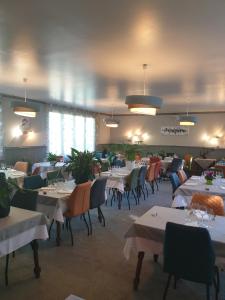 a dining room with tables and chairs and lights at Logis Doubs Rivage in Charette