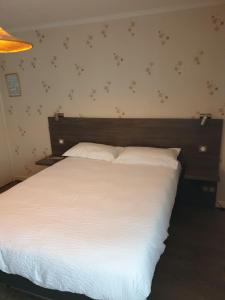 a bedroom with a white bed with a wooden headboard at Logis Doubs Rivage in Charette