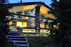 una cabaña de madera por la noche con las luces encendidas en Villa Vuossel, en Ruka