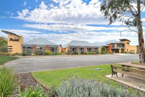 a park bench next to a street with houses at Strath Motel in Strathalbyn