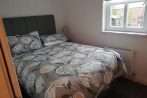 a bed with a comforter and pillows on it at Mews Apartment, Bushmills in Bushmills