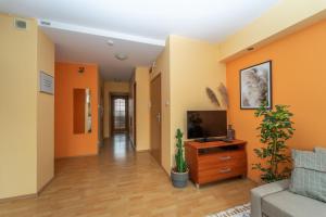 a living room with orange walls and a tv at Mariacki View Apartment in Gdańsk