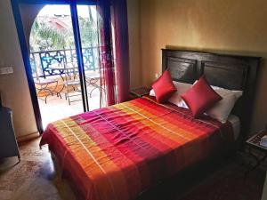 sypialnia z łóżkiem z czerwonymi poduszkami i balkonem w obiekcie La Perle de l'Atlas by Golf Resort w Marakeszu