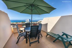 a balcony with a table and chairs and an umbrella at Residence Palm Garden Ocean View in Morro del Jable