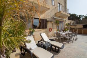 een patio met een tafel en stoelen en een gebouw bij Villa Mandolina in Għarb