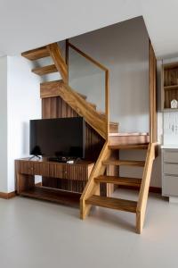a living room with a staircase and a tv at Apartamento Luxuoso à Beira-mar em Praia do Forte in Praia do Forte