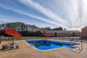 a swimming pool with a picnic table and a building at Red Roof Inn PLUS+ Huntsville – Madison in Madison