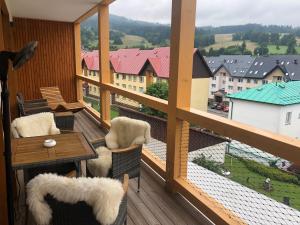 a balcony with a table and chairs and a view at JAVOR - Rezidence & Wellness in Železná Ruda
