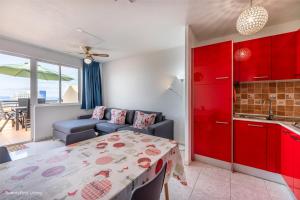 a kitchen and living room with red cabinets and a table at Residence Palm Garden Ocean View in Morro del Jable