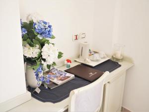 a desk with a laptop and a vase with blue and white flowers at Hotel Villa Ceselle in Anacapri