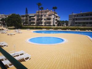 a large swimming pool with lounge chairs and a building at Dunas Mar in Alvor