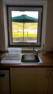 - un évier de cuisine avec une fenêtre et un parasol dans l'établissement Casa das Lajes - Alojamento Local, à Vila Nova de Foz Coa