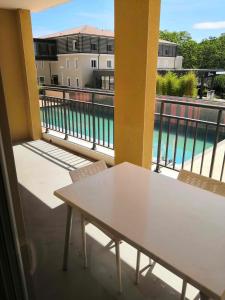 - Balcón con mesa y sillas y vistas a la piscina en Appartement T2 - Golf de Fontcaude - Résidence Coté Green à Juvignac 34990, en Juvignac