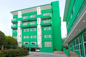 a green building with white windows next to a building at Wiz Hotel in Pattaya South