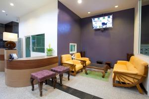 a waiting room with yellow chairs and a tv at Wiz Hotel in Pattaya South