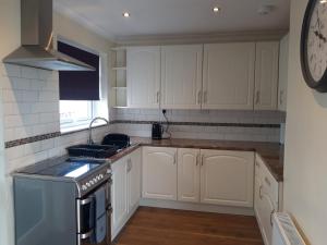 a kitchen with white cabinets and a stove top oven at Snowdonia View on Isle of Anglesey in Menai Bridge