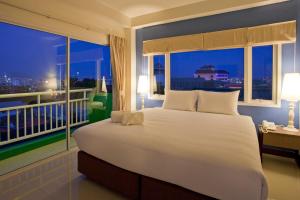 Un dormitorio con una gran cama blanca y una ventana. en Wiz Hotel, en Pattaya South 42 fotos más
