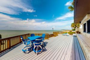 a deck with blue tables and chairs and the ocean at Anchors Away at North Shore in Port Isabel