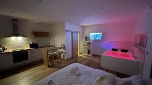 une chambre avec un lit et une cuisine avec un éclairage rose dans l'établissement Studio Balnéothérapie, à Wintzenheim