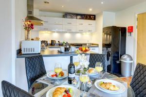 una cocina con una mesa con platos de comida y vino en City Centre Apartment with Secure Parking by MBiZ en Northampton