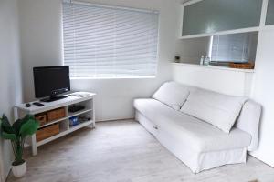 sala de estar con sofá blanco y TV en Ocean Views, en Huskisson