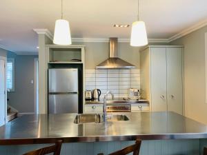 una cocina con fregadero y refrigerador en Kauri Cottage 2 or 3 Bedroom - Russell Cottage Collection, en Russell