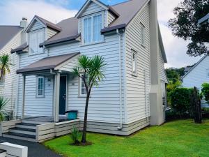 una casa blanca con una palmera delante en Kauri Cottage 2 or 3 Bedroom - Russell Cottage Collection, en Russell