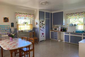 a kitchen with blue cabinets and a table and a refrigerator at Summer in the North of Sweden in Bjurholm