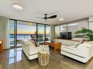 a living room with two white chairs and a flat screen tv at Seaview 31 Luxurious Beachside Two Bedroom Apartment in Seaview Resort with Stunning Views in Mooloolaba
