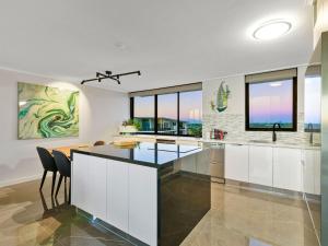 a kitchen with white cabinets and glass countertops at Seaview 31 Luxurious Beachside Two Bedroom Apartment in Seaview Resort with Stunning Views in Mooloolaba