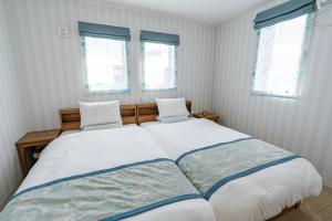 Un dormitorio con una cama grande con dos ventanas. en Ecot Irabu Bridge Sunset Hills, en Isla Miyako