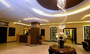 un vestíbulo con un jarrón de flores y una lámpara de araña en The Venue Resident, en Kuwait
