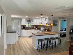 a kitchen with white cabinets and a island with bar stools at Gorgeous Seaside Seashell Cottage! in Hudson