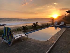 een zwembad naast het strand bij zonsondergang bij Casa Obe in Yolina
