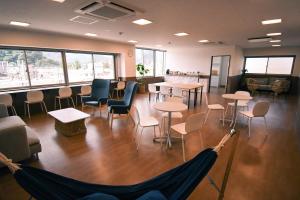 una sala d'attesa con tavoli, sedie e finestre di GATEWAY MAIZURU a Maizuru