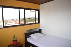 a bedroom with a bed and two windows at Casa Córa in Heredia