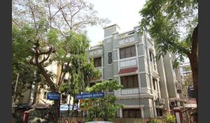 a tall white building with trees in front of it at Hotel Airlines International in Mumbai