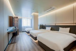 a hotel room with two beds and a bathroom at Amber Hotel Jeju in Jeju