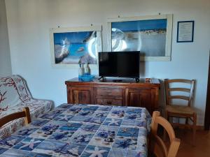 ブドーニにあるAppartamenti I Mandorliのベッドルーム(テレビ付)、テーブル、ベッド1台が備わります。