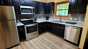 una cocina con armarios negros y electrodomésticos de acero inoxidable en The Pocono's Retreat with a Gameroom, Firepit, and Lake en Bushkill