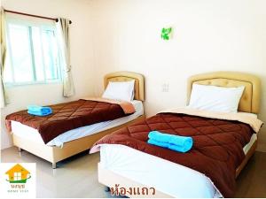 duas camas sentadas uma ao lado da outra num quarto em นงนุช โฮมสเตย์ & รีสอร์ท บุรีรัมย์ em Buriram