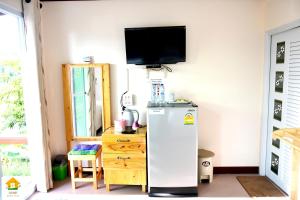 a kitchen with a refrigerator and a tv on the wall at นงนุช โฮมสเตย์ & รีสอร์ท บุรีรัมย์ in Buriram