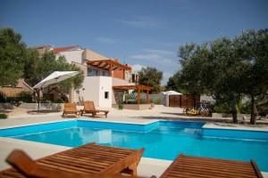 a swimming pool with two chairs and a house at Apartmani Olivia in Bibinje