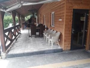 a wooden building with chairs and a table on a patio at Jaśkowa Chata Bieszczady apartament z basenem in Baligród