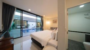 a bedroom with a large bed and a balcony at Lespalm Taraburi Pool Villa SHA Plus in Thalang
