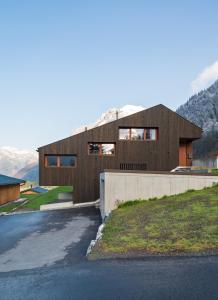 een houten huis op een heuvel met een oprit bij Apartment Hoamelig in Wald am Arlberg