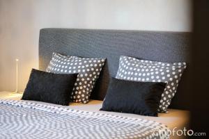 a bed with black and white pillows and a headboard at Apartments & Rooms Laganini in Zaton