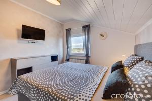 a bedroom with a bed and a tv on the wall at Apartments & Rooms Laganini in Zaton